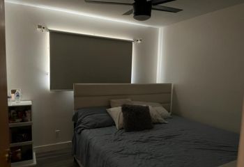 Bedroom featuring a large bed, soft pillows, and newly installed custom blackout roller shades on the window, providing a stylish and functional window treatment.