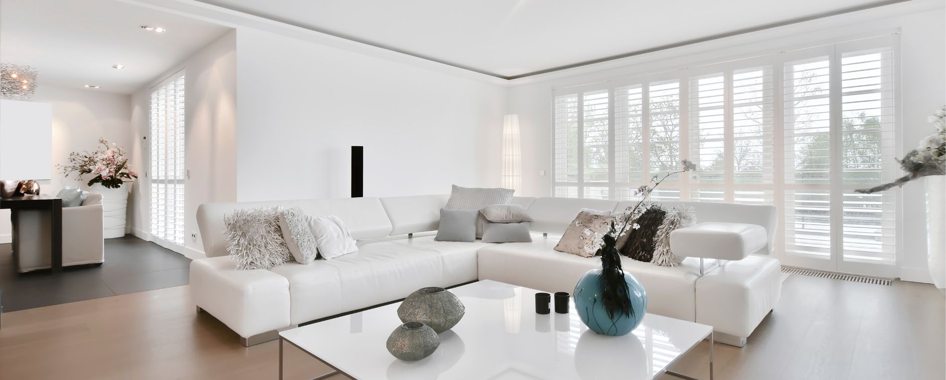 A view to a bright living room space with white plantation shutters